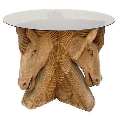 Lot 628 - A glass top table with a carved wood pedestal in the form of three horses' heads.