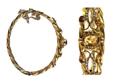 Lot 11 - An Edwardian 9ct gold citrine and seed pearl set hinged bangle.