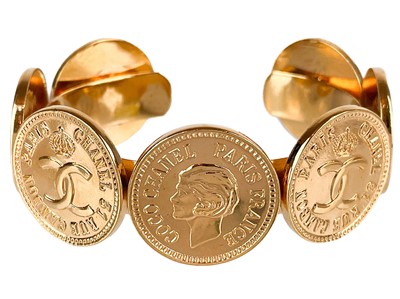 Lot 551 - A Chanel 1980's 24ct gold-plated CC and Coco Chanel medallion bangle.