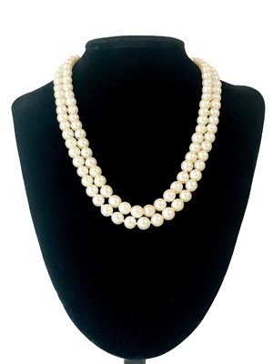 Lot 144 - A cultured pearl double-strand necklace with 9ct synthetic blue sapphire and white spinel clasp.