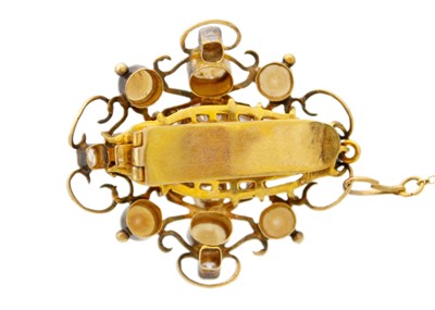 Lot 94 - An antique gold scroll brooch set with old mine cut diamonds, a central emerald and split pearls.