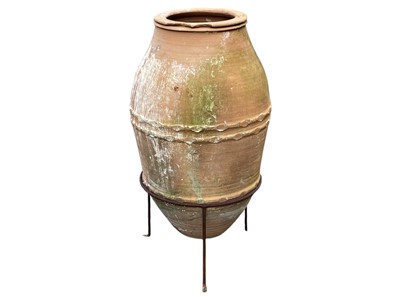 Lot 334 - A terracotta olive jar on a stand.