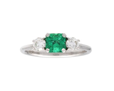 Lot 151 - An 18k white gold three-stone emerald and diamond set ring.