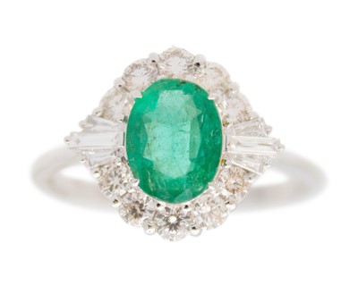 Lot 232 - An 18k white gold emerald and diamond cluster ring.