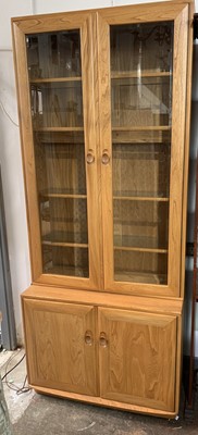 Lot 3169 - An Ercol elm cabinet, with two glazed doors....