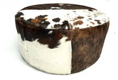 Lot 3059 - A circular pouffe upholstered in cow hide....