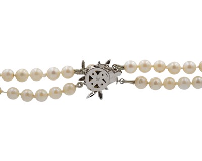 Lot 23 - A double-row cultured pearl necklace, strung to a 14k white gold diamond and pearl set clasp.