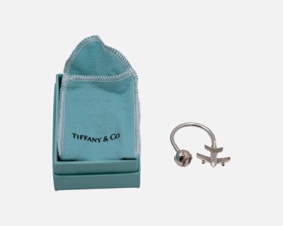Lot 106 - TIFFANY & CO - A 925 silver keyring, in the form of a globe and aeroplane, with box and pouch.