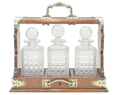 Lot 76 - An Edwardian oak three bottle tantalus.