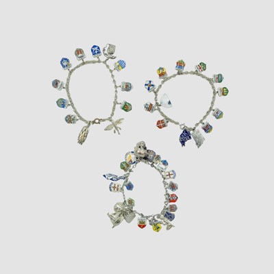 Lot 62 - Three silver and white metal charm bracelets, each with many enamel souvenir charms.