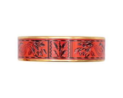 Lot 101 - HERMES - A gold-tone red flora decorated enamel bangle.