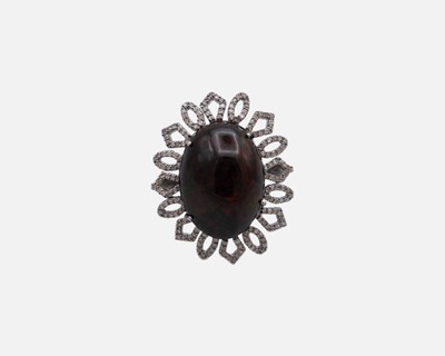 Lot 35 - A silver dress ring set with a large oval cabochon dyed black opal, surrounded by melee diamonds.