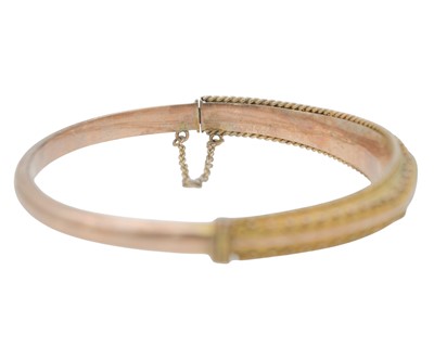 Lot 3 - An Edwardian 9k rose gold Etruscan Revival diamond and blue gem set hinged bangle.
