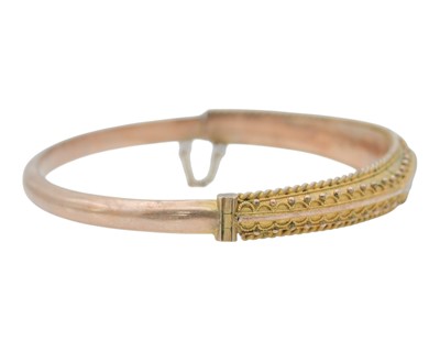 Lot 3 - An Edwardian 9k rose gold Etruscan Revival diamond and blue gem set hinged bangle.