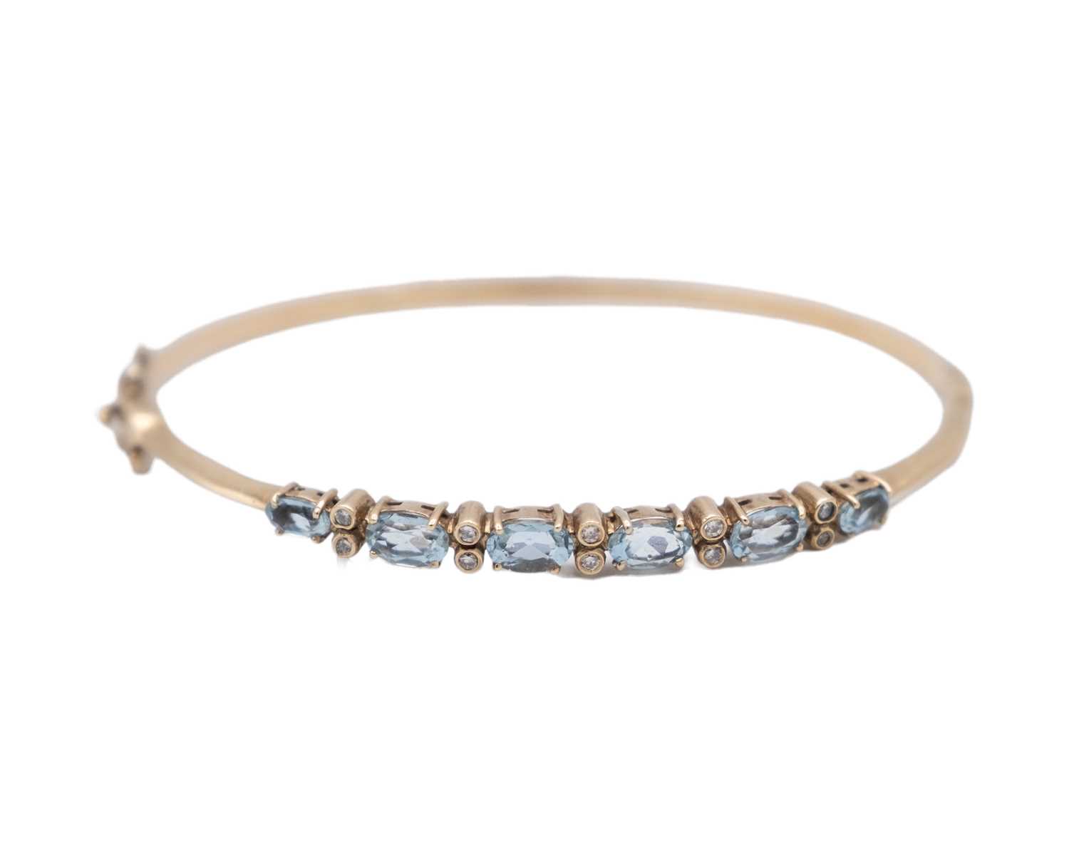 Lot 16 - An attractive 9k hallmarked gold oval cut aquamarine and diamond set hinged bangle.