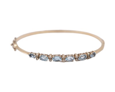 Lot 16 - An attractive 9k hallmarked gold oval cut aquamarine and diamond set hinged bangle.