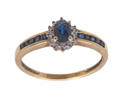 Lot 169 - A modern 9k oval blue sapphire and diamond set cluster ring.