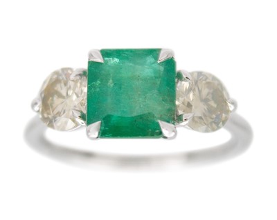 Lot 113 - A Platinum 3-stone ring set with an emerald-cut emerald and diamonds.