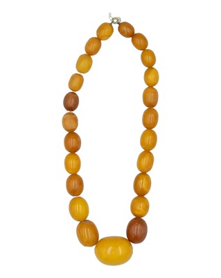 Lot 241 - An egg-yolk amber graduated oval bead necklace.