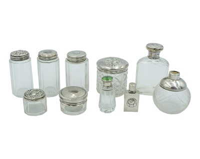 Lot 80 - A medley of Victorian and later silver-lidded scent bottles and cosmetic jars.