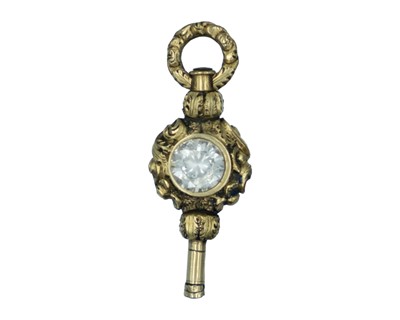 Lot 567 - A 19th-century gold fancy watch winder key, set with a round cut white gemstone.