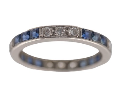 Lot 204 - A platinum round-cut diamond and calibre-cut blue sapphire set full eternity ring.