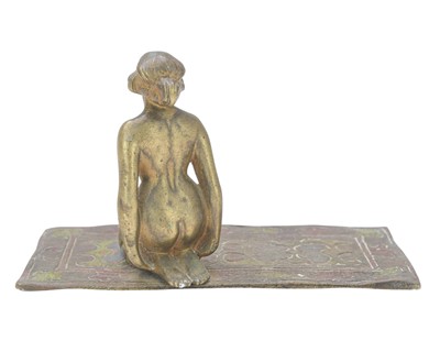 Lot 24 - A cold painted bronze figure of a female nude kneeling on a carpet.