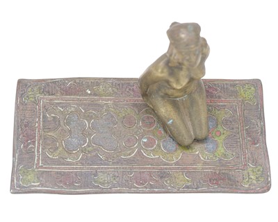 Lot 24 - A cold painted bronze figure of a female nude kneeling on a carpet.