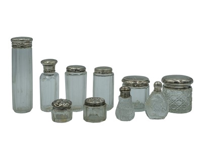 Lot 155 - A selection of Victorian and later silver-lidded cosmetic jars and scent bottles.