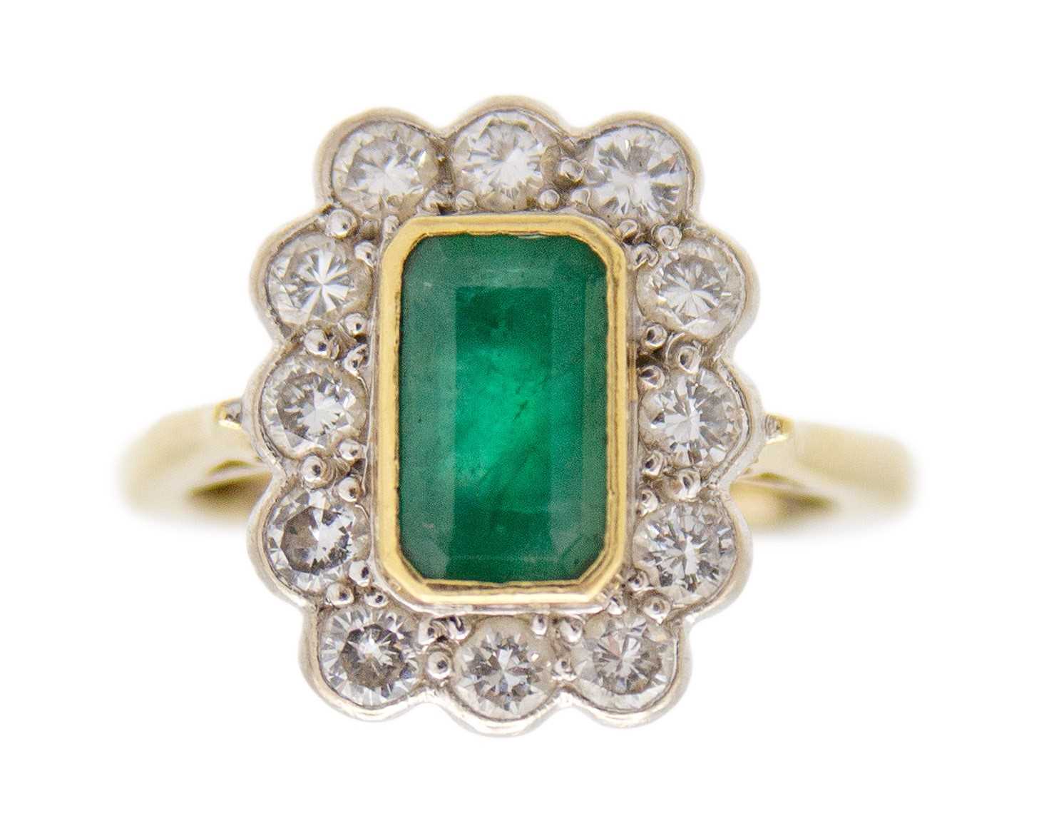 Lot 106 - An emerald and diamond set gold and platinum cluster ring.