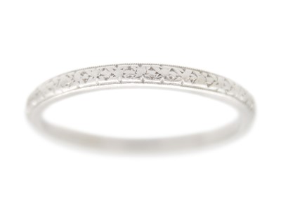 Lot 122 - An Art Deco platinum band ring, with banded and carved decoration.