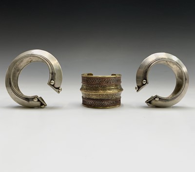 Lot 292 - Two silver tribal bangles and a brass cuff, Laos.