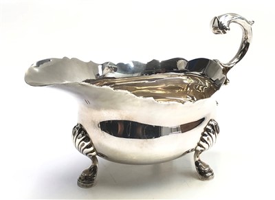 Lot 2056 - A silver sauce boat with scrolling handle,...