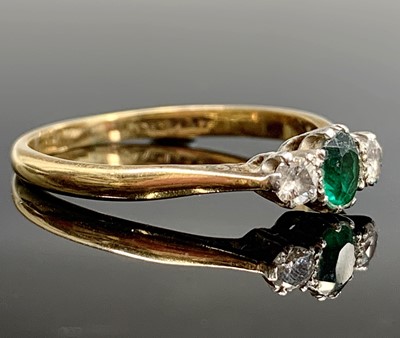 Lot 740 - An 18ct gold ring set an emerald and two...
