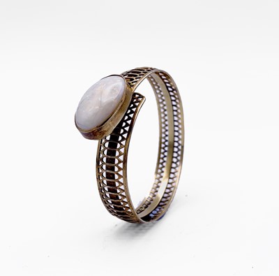 Lot 78 - A pierced silver gilt bangle set a large white opal.