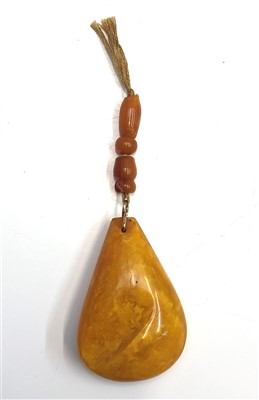 Lot 2468 - An amber pear shaped pendant with rudimentary...