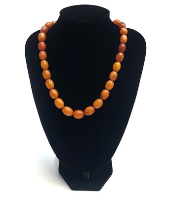 Lot 2469 - An amber necklace, the largest bead 18mm long,...