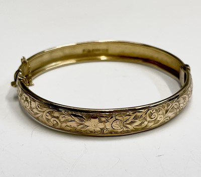 Lot 431 - An Edwardian 9ct gold hinged engraved bangle...