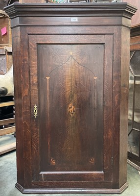 Lot 3188 - A George III oak corner cupboard, the panel...