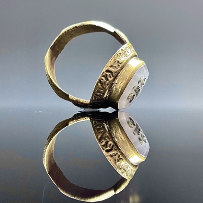 Lot 688 - A cast bronze ring set with an oval white...