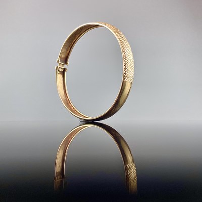 Lot 553 - A 9ct gold bangle with textured front, weight...