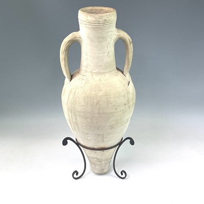 Lot 210 - A terracotta twin handled storage jar on a...