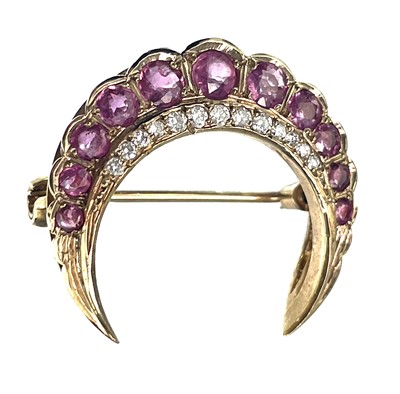 Lot 7 - A modern 9ct gold diamond and ruby crescent brooch