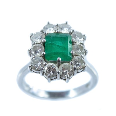 Lot 143 - An 18ct white gold emerald and diamond cluster ring.