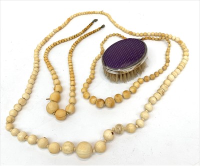 Lot 2457 - Three ivory necklaces and a silver mounted brush.