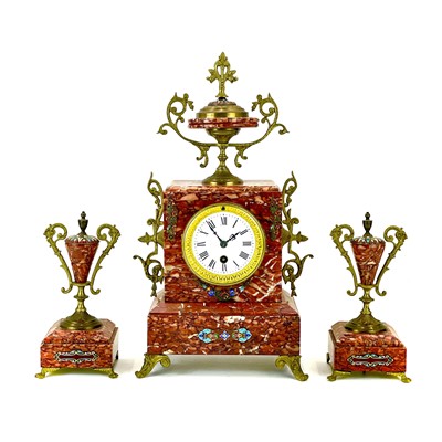 Lot 1706 - A French rouge marble, gilt metal and champleve enamel clock garniture.