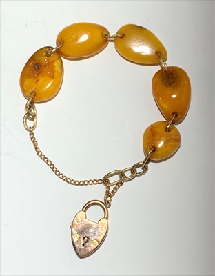 Lot 2592 - A 9ct gold and amber bracelet with padlock clasp.